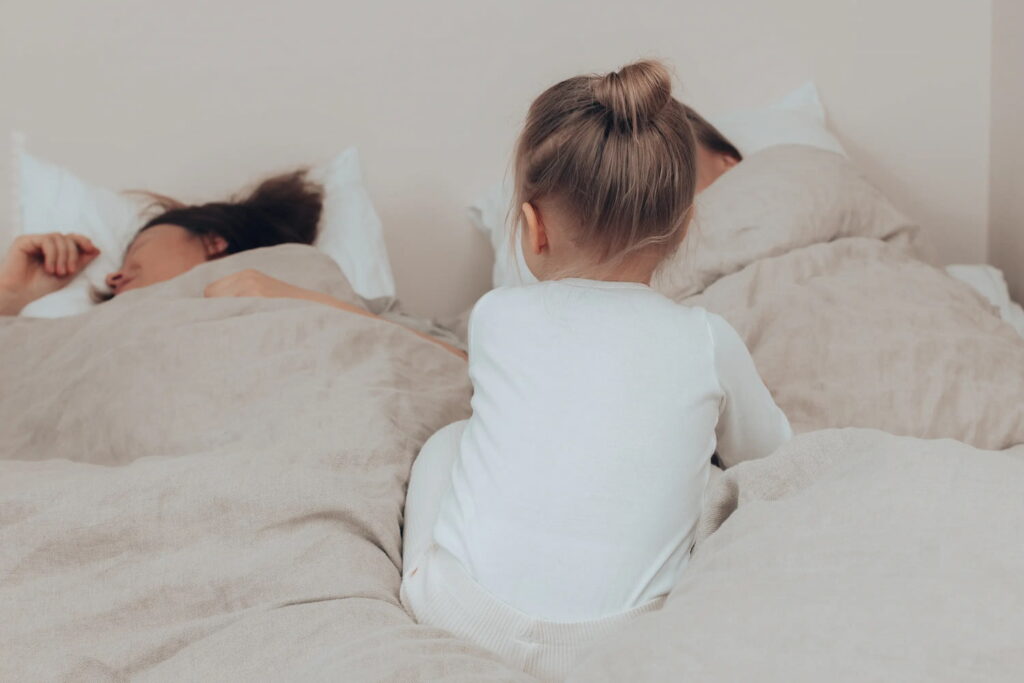Lapsi ja vanhemmat sängyssä